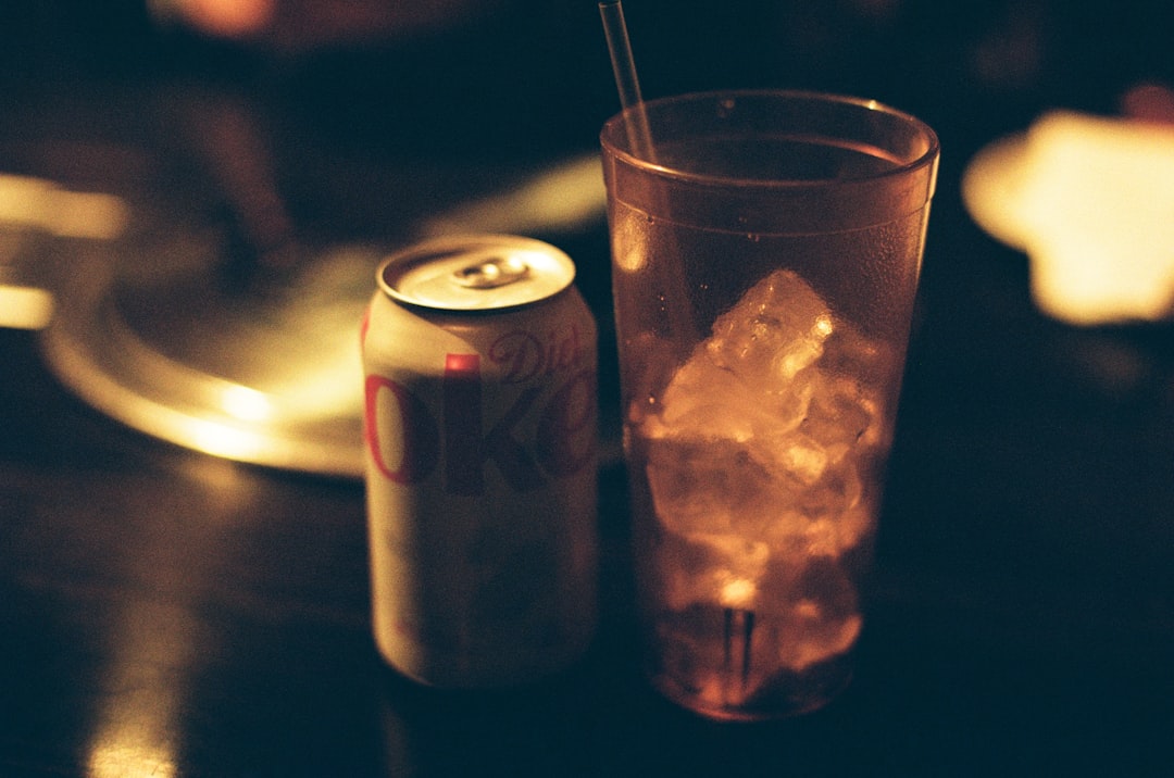 Glass of soda and a soft drink can representing sugary drinks and fructose in gout risk.